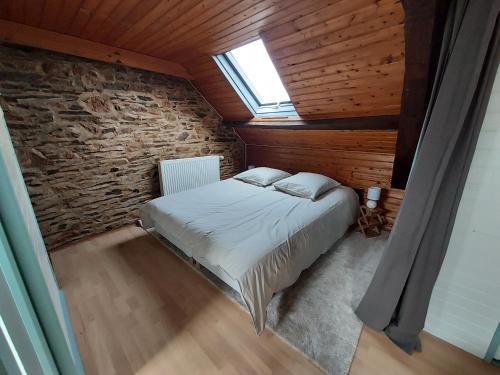 Le PinGites de la Janais的卧室配有砖墙内的床铺