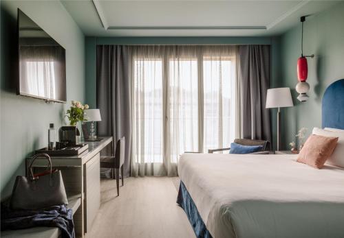 圣塞瓦斯蒂安Hotel Antik San Sebastián的配有一张床、一张书桌和一扇窗户的酒店客房