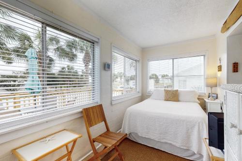 拉古纳海滩Linda's Cozy Cottage "C"的一间卧室配有一张床、一把椅子和窗户。