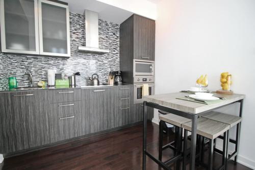 多伦多Presidential 2+1BR Condo, Entertainment District (Downtown) w/ CN Tower View, Balcony, Pool & Hot Tub的厨房配有木制橱柜和台面