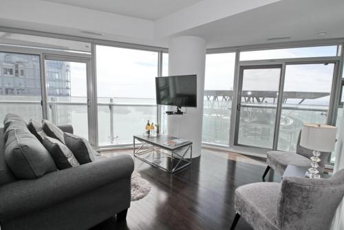 多伦多Presidential 2+1BR Condo, Entertainment District (Downtown) w/ CN Tower View, Balcony, Pool & Hot Tub的客厅配有沙发、椅子和电视