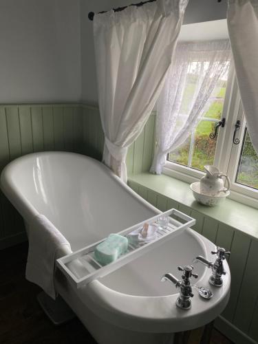邓吉文Christie's Cottage的带窗户的浴室内的白色浴缸