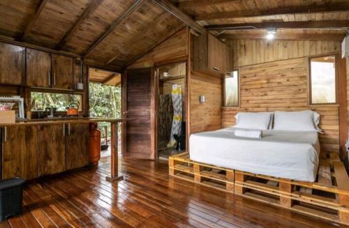 圣埃伦娜Cabaña en Medio del Bosque con Jacuzzi - Santa Elena的小木屋内一间卧室,配有一张床