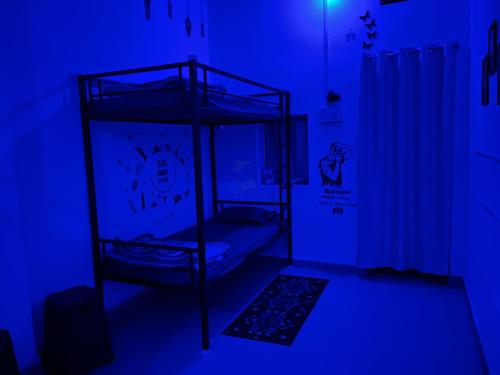 乌贾因Spiritual Backpackers Hostel的一间设有两张双层床的蓝色灯光客房
