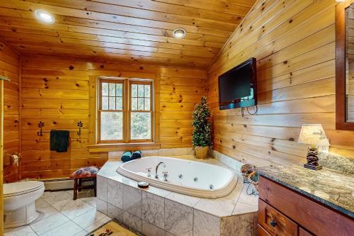 纽里Sunday River Ridge的带浴缸的浴室和木墙电视。