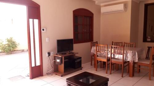 佩洛塔斯Sobrado na Praia do Laranjal的客厅配有电视和桌椅