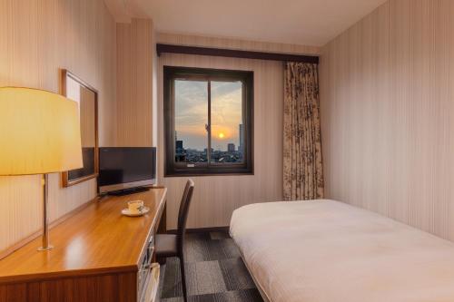 泉佐野王子空港城市酒店的配有一张床、一张书桌和一扇窗户的酒店客房