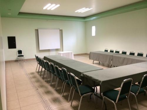 CuauhtémocTarahumara Inn的一间会议室,配有桌椅和屏幕