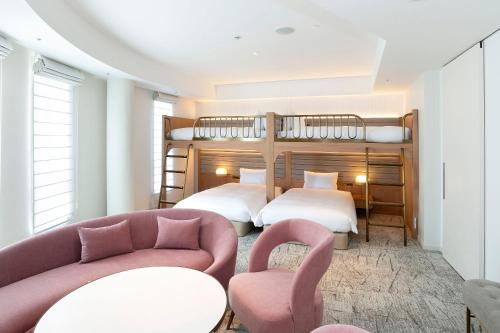 横滨Hotel Comento Yokohama Kannai的一间卧室配有两张床、一张沙发和椅子