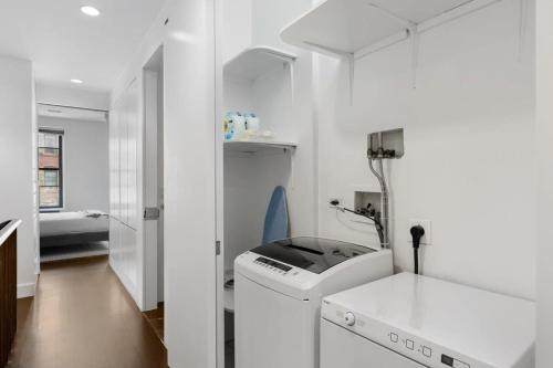 纽约Chelsea Canvas II by RoveTravel Large 3BR Duplex的白色的浴室设有洗衣机和水槽。