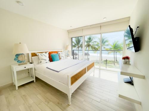 蓬塔查梅Olas del Mar by Playa Caracol Residences的白色的卧室设有床和大窗户