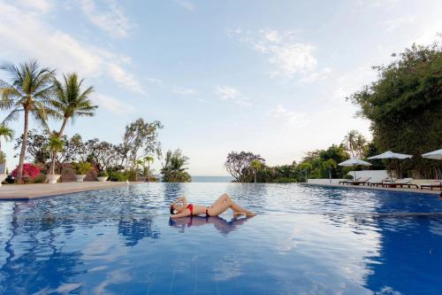 美奈维多利亚潘切海滩Spa度假酒店的躺在度假村游泳池中的女人