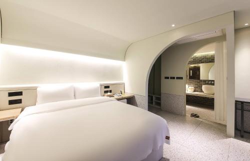 釜山MUTE HOTEL的一间带白色大床的卧室和一间浴室