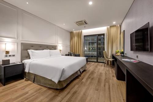 岘港Goldenbay Danang 1 Bedroom Apartment的卧室配有一张白色大床和电视。