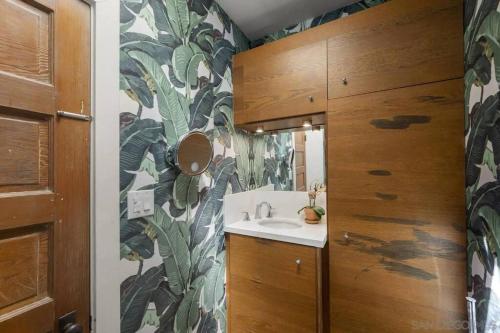 圣地亚哥Cute Hillcrest cottage的一间带水槽和绿叶壁纸的浴室