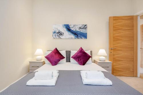 梅登黑德Luxury Apartments 2 Bedrooms Central Maidenhead的一间卧室配有一张带紫色枕头的大床