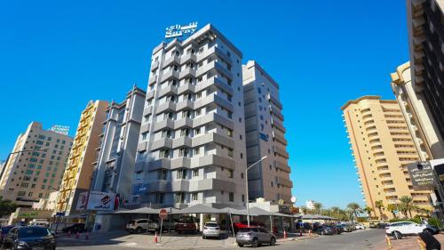 科威特Saray Hotel Apartments的一座高大的建筑,有汽车停在城市里