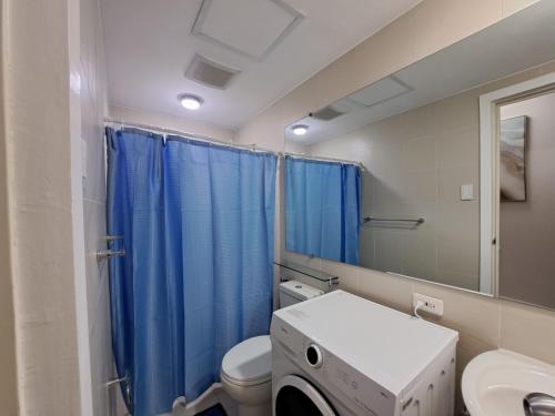 圣费尔南多Hailey's Crib @ Azure North的浴室设有卫生间和蓝色的浴帘。