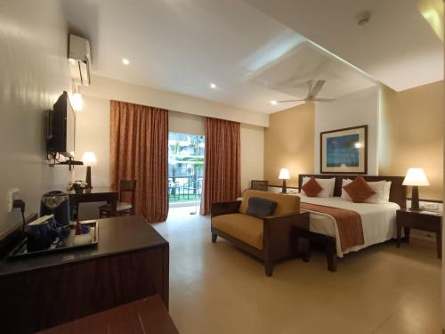 卡兰古特Kyriad Prestige Calangute Goa by OTHPL的配有一张床和一把椅子的酒店客房