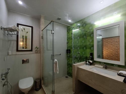 卡兰古特Kyriad Prestige Calangute Goa by OTHPL的带淋浴、水槽和玻璃淋浴间的浴室
