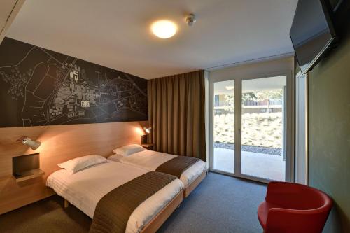 洛桑瑞士科技酒店的酒店客房,配有一张床和一张红色椅子