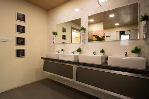 浦那Hostells的一间带三个水槽和大镜子的浴室