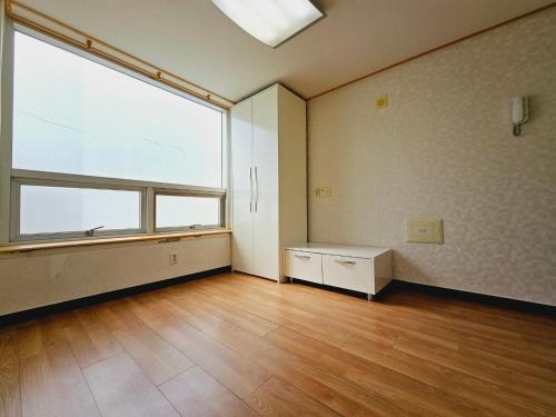 釜山D&D PineVill的空空房间设有大窗户和木地板
