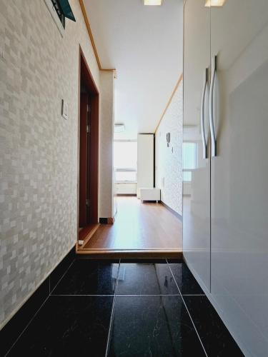 釜山D&D PineVill的走廊上设有黑色瓷砖地板和门