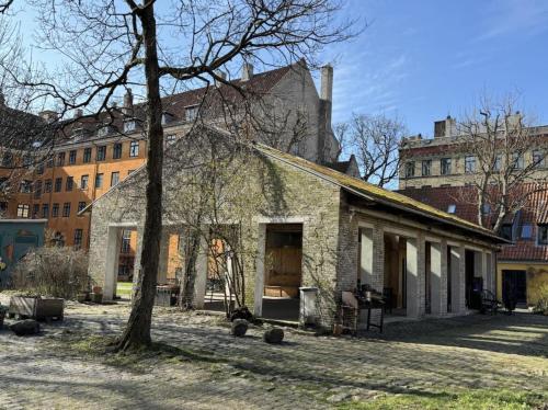哥本哈根ApartmentInCopenhagen Apartment 1594的一座古老的石头房子,有树和建筑