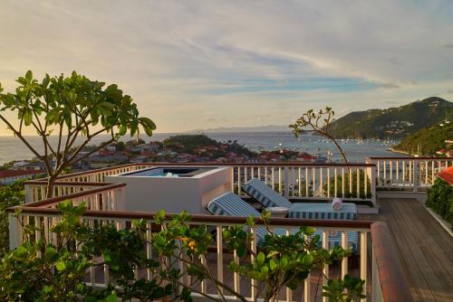 古斯塔维亚Hôtel Barrière Le Carl Gustaf St Barth的阳台配有椅子,享有水景