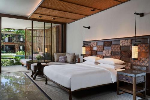 沙努尔Andaz Bali - a Concept by Hyatt的一间卧室配有一张大床和一张沙发