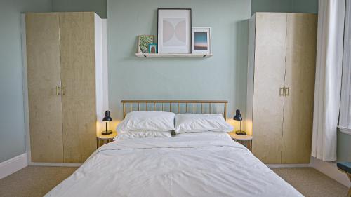伯恩茅斯Burlington Mansions - Stunning Coastal Apartment的一间卧室配有一张带两盏灯和两个橱柜的床。