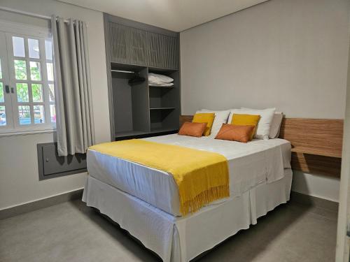 圣劳伦斯海滨Flat na Riviera de São Lourenço com serviço de hotelaria的卧室配有一张带黄色枕头的大型白色床。