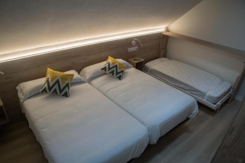 龙塞斯瓦耶斯Posada de Roncesvalles的小客房内的两张床,配有白色床单
