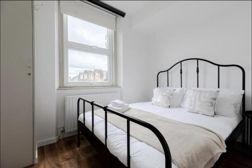 伦敦Primrose Hill Charming 1-Bed Flat的卧室配有一张黑白床和窗户