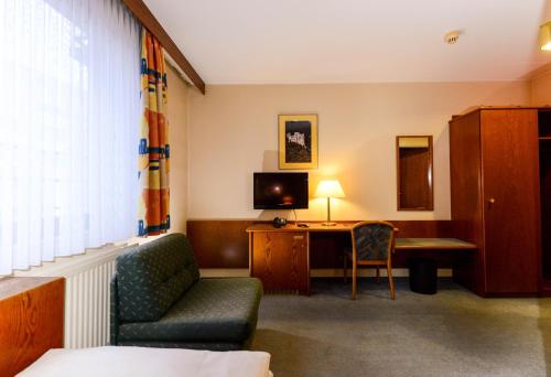 卢森堡APPART-HÔTEL MARCO POLO的酒店客房设有一张沙发和一张带电视的书桌。