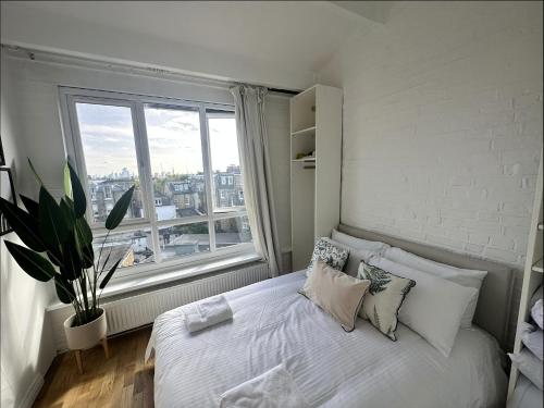 伦敦Primrose Hill Apartment with Balcony的卧室配有白色的床和大窗户
