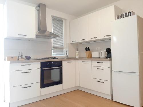 伊佐拉Apartments Amavi的白色的厨房配有白色橱柜和炉灶。