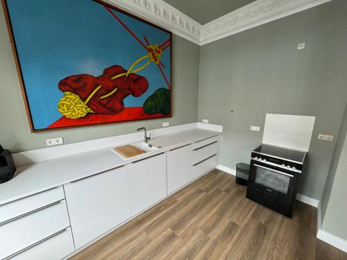 汉堡Art Apartments的厨房配有白色橱柜,墙上挂有绘画作品