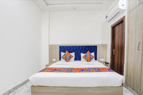 TājganjFabHotel Taj Avenue的卧室配有一张带彩色枕头的大型白色床。