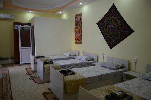 布哈拉Orzu Guest House的一间设有四张床的客房和一张带照片的墙壁