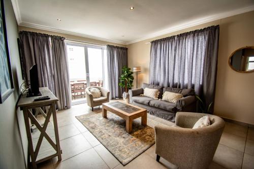 LangstrandLong Beach Selfcatering Namibia的客厅配有沙发、椅子和电视