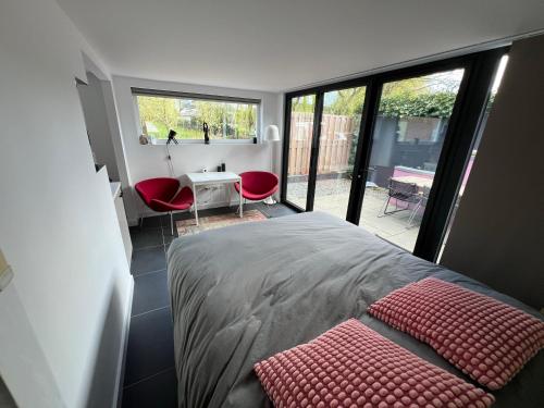 杜斯堡纳因内克住宿加早餐旅馆的一间卧室配有一张床和一张带红色椅子的桌子