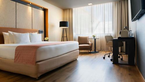 墨西哥城NH系列墨西哥城机场T2航站楼酒店的酒店客房设有一张大床和一张书桌。