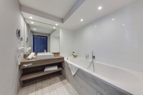 列日Van der Valk Hotel Liège Congres的白色的浴室设有浴缸和水槽。