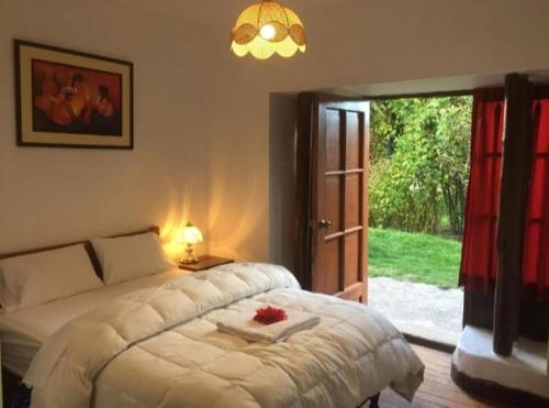库斯科El Jardín de Jeni的卧室配有白色的床和滑动玻璃门