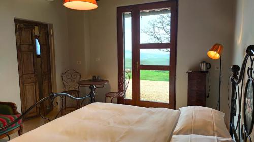 渥尔特拉Podere Campiano的一间卧室配有一张床,一扇门设有窗户
