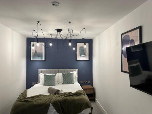 彼得伯勒Newark House Premium Apartments by DH ApartHotels的一间卧室配有一张带蓝色墙壁的大床