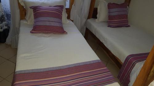 迪亚尼海滩Tranquil Pendo villas的两张带条纹枕头的床