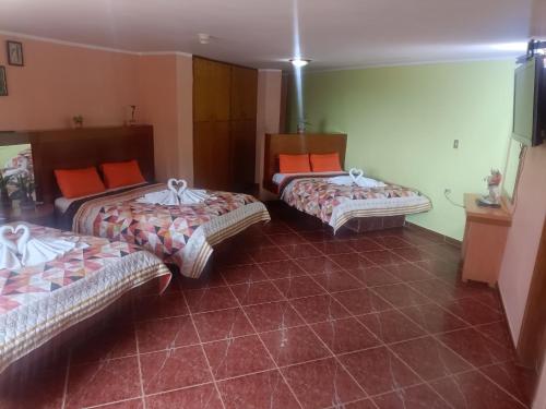 MacutoHotel El Ceibo的带3张床和橙色枕头的客房